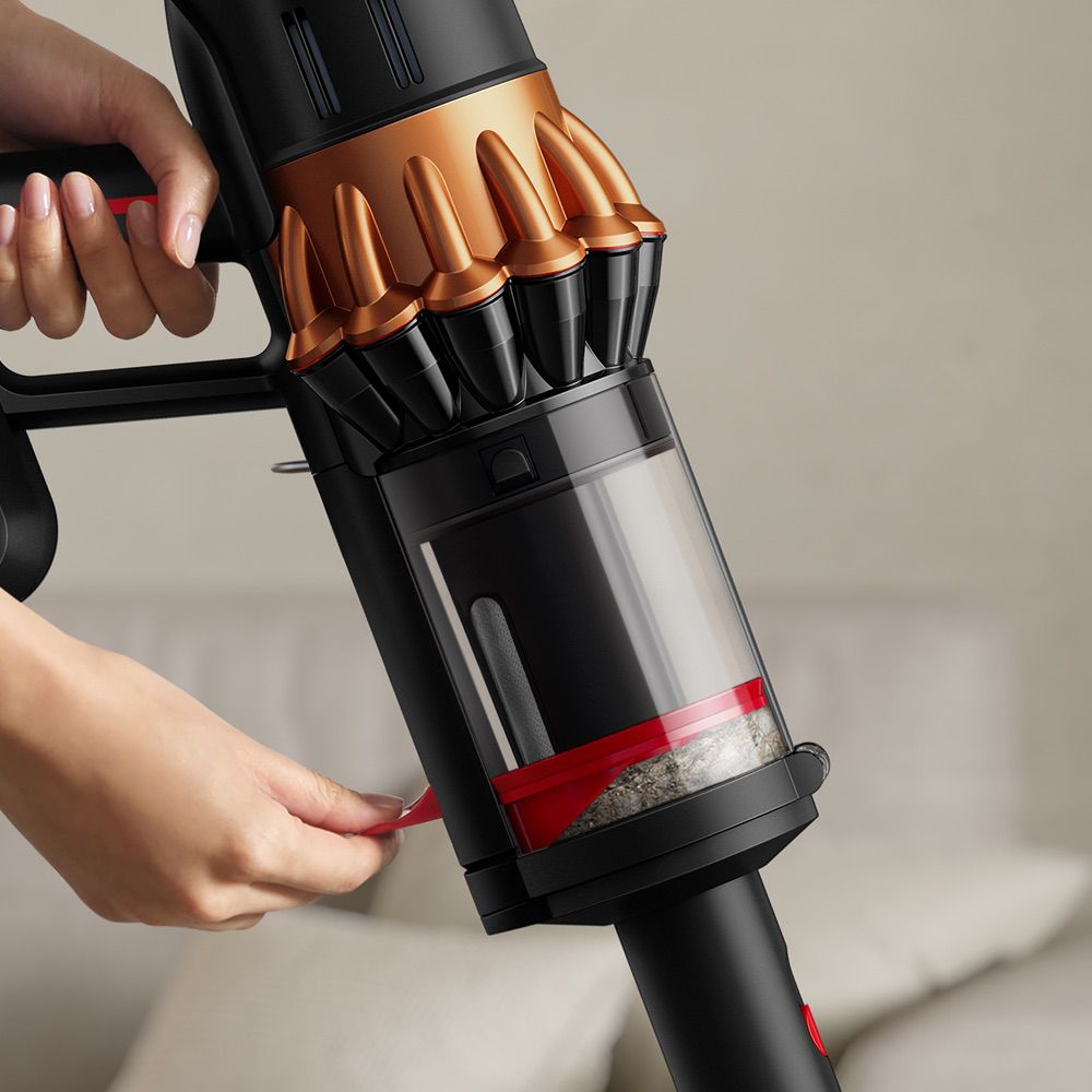 A person wipe-clean emptying the dirt inside the bin of the Dyson Piston Animal vacuum - using the lever on its side.