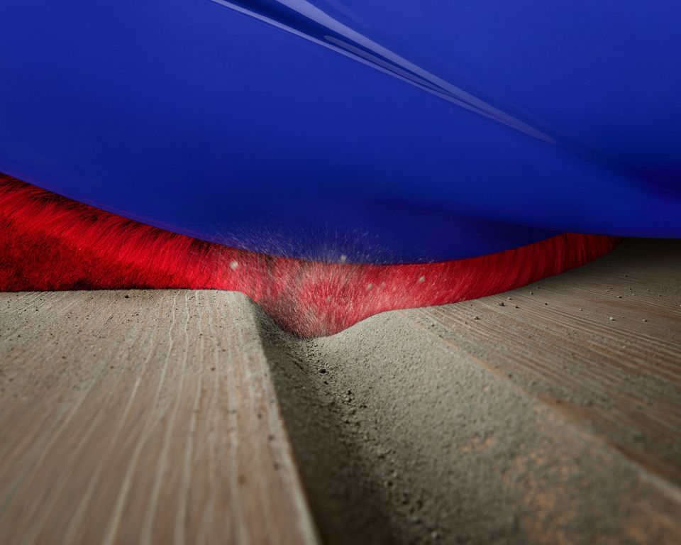 Soft fibres cleaning dust from a ridge in the floor.